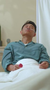 Çinli Maole hastası, hastane yatağında uzanıp acı veren semptomlarla meditasyon yapıyor. Sağlık, hastane, ilaç konsepti.