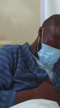 Hastanedeyiz. Işıklar kapansın. Zayıf, sağlıksız, maskeli bir Afro-Amerikan hasta hastane yatağında koronavirüs semptomları göstererek ölüyor. Covid-19 salgını.