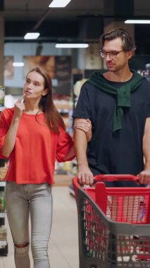 Süpermarkette yürüyen genç ve yakışıklı bir çift gıda ürünleri marketi tüketimini seçerek besin maddeleri hakkında iletişim kuruyor..