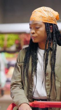 Konsantre olmuş Afro-Amerikan müşteri süpermarketin doğal meyve bölümünde yürüyen genç kadın yiyecek alışverişi için taze portakal seçiyor..