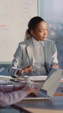 Profesyonel bir kadın, dizüstü bilgisayarı ve kahvesiyle masada oturur, işine odaklanmış ve işine dalmış görünür, kendine güveni ve hırsı somutlaştırır.