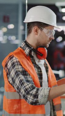 Bu video, güvenlik donanımlı bir inşaat işçisinin gününün nasıl geçtiğini gösteriyor, güncellemeler için bir tablet inceliyor, ve doğruluğu sağlamak için planlar gözden geçiriliyor