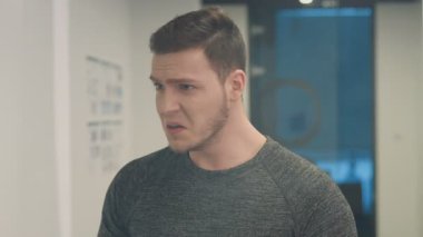 Dumanlı ofiste çalışan çalışanlar. Kızgın adam yangın söndürücü getiriyor ve bilgisayarı kırmaya çalışıyor. Duman temizleniyor, adam şaşırmış görünüyor..