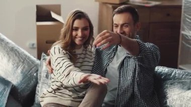 Neşeli bir çift yeni evlerinin anahtarlarıyla mutlu bir şekilde poz verip yeni evlerini kutluyorlar.