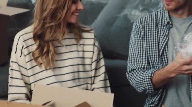 Neşeli bir çift neşeli bir şekilde baloncuklu naylon paketleri açıyor.