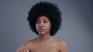 Gülümseyen, kıvırcık saçlı, sanal ekranla çalışan güzel Afro-Amerikan kadın. Gri arka planda izole edilmiş teknolojiyi kullanan Etiyopyalı üstsüz kızın portresi.