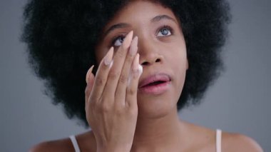 Yüzüne kozmetik köpük sürüp neşe içinde gülümseyen güzel, egzotik Afrikalı Amerikalı genç bir kadın. Güzel yüz derisi konsepti için profesyonel kozmetik ürünleri.