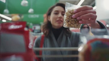 Bir kadın süpermarkette fındık seçer alışveriş merkezi satın alır, sağlıklı ürünler, perakende aile, genç, güzel, mutlu, hipermarket, yavaş çekim.