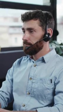 Kendini işine adamış bir erkek müşteri hizmetleri acentesi telefonda, odaklandığını ve görevine bağlılığını gösteriyor.