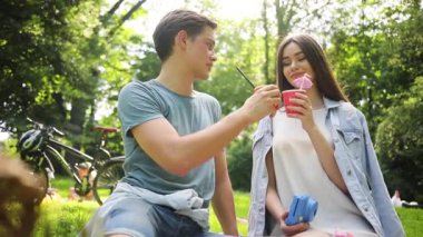 Piknikte aşık güzel beyaz bir çift. Pipetle meyve suyu içen, çekici genç bir adamla konuşan tatlı bir kız. Romantik anlar. Gündüz vakti. Yaz zamanı. Açık havada. Gençlik.