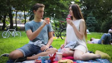 Piknikte aşık beyaz bir çift. Kız arkadaşının elini tutan, buket veren yakışıklı bir öğrenci. Minnettar kız kucaklayan erkek arkadaş. - Sürpriz. Çıkmak. Açık havada..