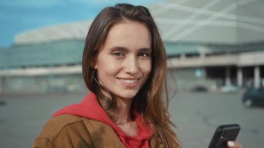 Neşeli ve hayat dolu bir şehir ortamında akıllı telefonuyla aktif olarak meşgul olan genç bir kadın hayattan zevk alıyor.