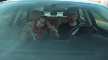 Duygularını ve etkileşimlerini canlı bir şekilde yakalayan, aynı aracı paylaşan iki kişinin dinamik bir sahnesi.