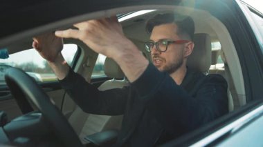 Genç bir adam araba sürerken aşırı derecede odaklanır, hem konsantrasyon hem de şık bir davranış sergiler.