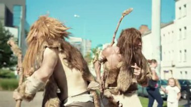 İlkel ve tarihsel giysilerdeki iki figür büyüleyici bir performansta farklı zaman aralıklarıyla harmanlanır