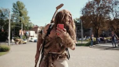 Kaprisli bir karakter doğada akıllı bir telefonu neşe içinde kullanırken yaratıcı giysiler giyer.