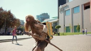 Mağara adamı karakteri günümüzün ve geçmişin kesişimlerini gösteren modern bir dönüşümle yemek dağıtır..