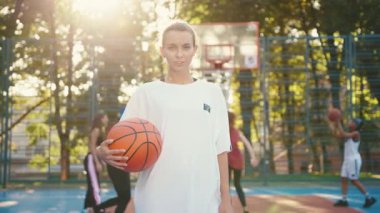 Genç bir atlet, altın saat boyunca canlı bir sahada basketbol topuyla poz veriyor, tutku ve enerji gösterisi yapıyor..