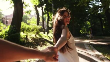 Kapalı el ele tutuşan erkek, kadının elini tutar, gülümser, gün batımında mutlu hisseder, güneş ışığı, beyaz bir aile, dışarıda neşeli aşıklar, genç, eğlenceli erkek arkadaş, şehir arkadaşlığı, arkadaşlık randevusu.