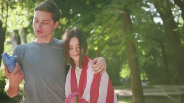 Çekici çift yürüyüşü mutlu adam Amerikan bayrağıyla fotoğraf çekiyor gün batımında güneş batımında ağır çekim beyaz aile eğleniyor neşeli aşıklar dışarıda eğleniyor genç erkek arkadaş şehir arkadaşlığı randevusu