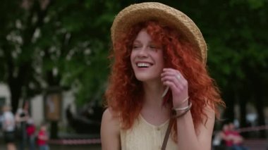 Şehrin sokaklarında yürüyen kızıl saçlı genç bir kadının portresi gülümsüyor. Mutlu, yavaş çekim yaz yüzleri. Kafkas teknolojisi.