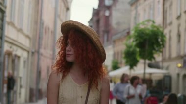Yüzünüzü kapatın. Genç, gülümseyen, kızıl saçlı, sokaklarda yürüyen mutlu, yavaş çekim yaz yüzleri teknolojisi. Kafkasyalı, güzel, açık hava kadın portresi.