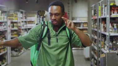 Yeşil çantalı teslimatçı çocuk markette dans edip maaş günü maaşını kutluyor. Başarı konsepti.