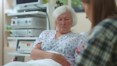 Hasta büyükannesine hastanede yardım eden genç bir kadın acı çeken bir hastalığa yakalandı. Torunu büyükannesine su ve hap veriyor. Sağlık hizmetleri. Destek konsepti.