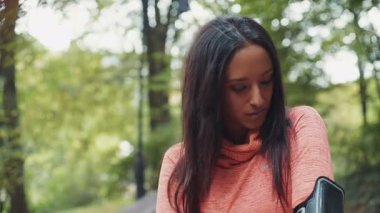 Genç bir Mulatta kadın koşucusunun portresi durdu ve parkta telefonunu kullandı. RED Epic Camera 'da Çekim.