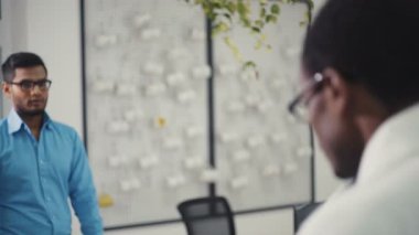 Mavi gözlüklü bir adam ofise girer, arkadaşını tebrik eder, iş yerinde oturur. RED Epic Camera 'da Çekim.