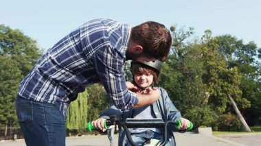 Şefkatli bir baba, oğlunun kaskını takmasına yardım eder.