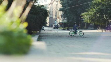 Parkta yeşil bisiklet süren kask takan sevimli küçük bir çocuk. Bisiklette oturan çocuk. Yaz zamanı. Açık havada.
