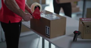 Kafkasyalı iki üniformalı adam depoda müşteri paketleriyle teslimat kutuları topluyor. Hizmet insanları.