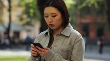 Zeki telefon kullanan genç Asyalı kadını kapatıyorum. Sokak kızı, internet teknolojisi alışverişi yapıyor. Çinli, mobil Çin malı, cep telefonlu, yavaş çekim yapan gözler.