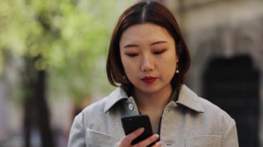 Kapat yüzünü, genç Asyalı kadın telefon kullan, kameraya bak, sokak kızı, internet alışverişi, Çin cep telefonu, cep telefonu işi, yavaş çekim.