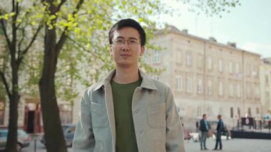 Gözlüklü yakışıklı Asyalı adam telefonda konuş mutlu sokak şehir merkezinde gün batımında modern, çekici, yakışıklı, başarılı, cep telefonlu, ağır çekimli Japon portresi.