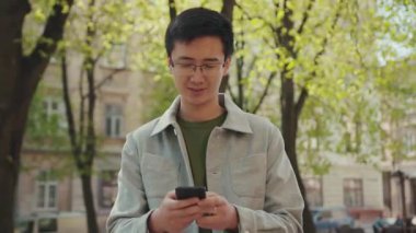 Yakışıklı genç adam, gözlüklü Asyalı 'yı gezdir. Mutlu sokak şehir merkezini kullan. Gün batımı, gündelik modern, çekici, başarılı, başarılı, cep telefonu, Japon yavaş çekim portresi.