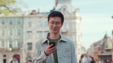 Tatmin olmuş genç adam, gözlüklü Asyalı 'yı gezdir. Mutlu sokak şehir merkezini kullan, gün batımını izle. Modern, çekici, başarılı, cep telefonu.