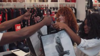 NEW YORK - 5 Nisan 2017: Mutlu kıvırcık saçlı arkadaşlar alışveriş merkezlerinde el çantalarını birlikte alın Afro-Amerikan kadın gülümseyin moda kızı teknolojisi güzel kadın giyim tüketiciliği