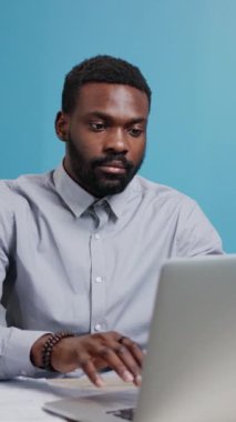 Dizüstü bilgisayarıyla uğraşan profesyonel bir adam, canlı bir çalışma alanına yoğunlaşmayı ve kararlılığı somutlaştırıyor..