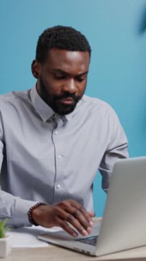 Bir adam, modern ve çağdaş ofis ortamını gösteren bir dizüstü bilgisayarla meşgul.