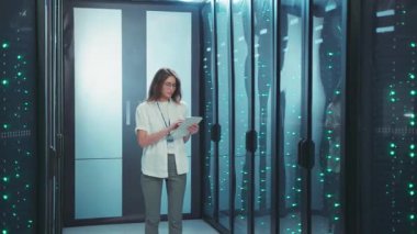 Bir teknisyen, yüksek teknolojili sunucu odasındaki bir tabletin veri ölçümlerini inceliyor.