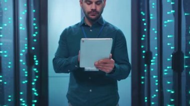 Bir adam, aydınlanmış arka planlara sahip çağdaş, veri dolu bir çevrede tablet kullanmakla meşgul.