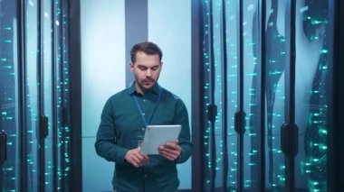 Odaklanmış bir profesyonel, veri sunucularıyla çevriliyken, modern teknolojiyi gösteren bir tablet kullanır..