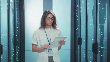Sunucu odasında profesyonel bir kadın yoğun odaklanma ve hassasiyetle tablet üzerindeki karmaşık verileri analiz ediyor.