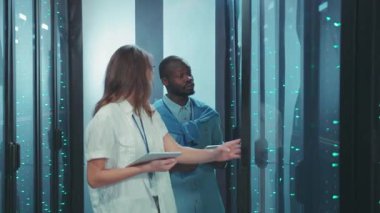 Sofistike bir modern veri merkezi içindeki veri sunucularını titizlikle inceleyen ve analiz eden iki yetenekli profesyonel