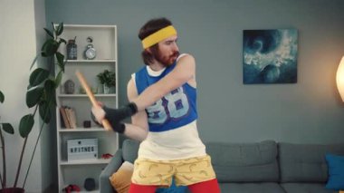 Eğlenceli bir geçmişe dönük spor meraklısı içeride spor sopasıyla eğlenceli bir poz veriyor ve renkli bir kıyafet giyiyor.