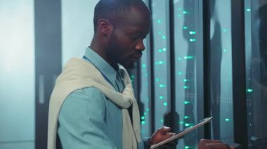 Profesyonel bir adam, yenilik ve yaratıcılığı gösteren modern, teknolojik bir ofis alanında bir tabletle meşgul olur.