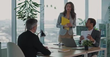 Beyaz tenli yetişkin bir çalışan, yeni açılan şirkette modern bir iş için başvuruyor. Birkaç yönetici CV 'ye bakıyor ve anlaşmanın detaylarını tartışıyorlar.