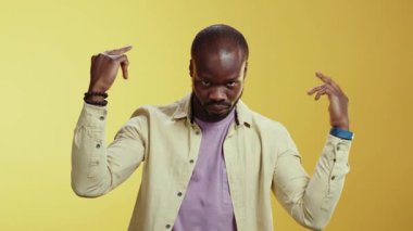 Bu video, esmer ceketli ve mor gömlekli bir adamın oyuncu kişiliğini sarı arka planda sergilediği komik anları gösteriyor.